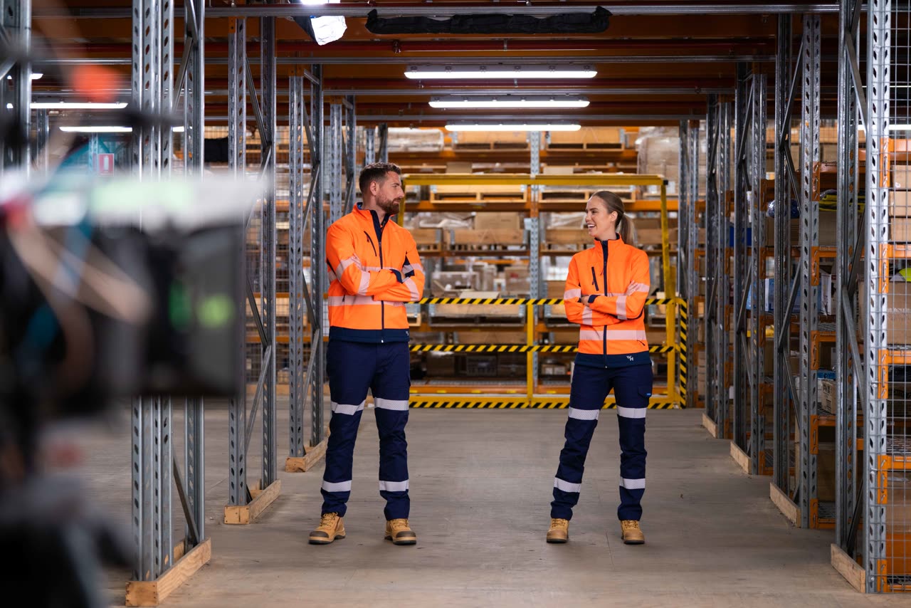 Two workers in Workhorse hi-vis workwear filmed between warehouse racking