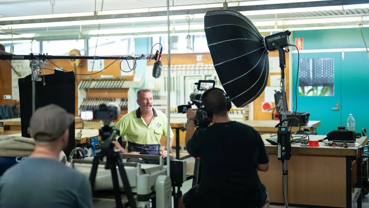 Ivory Media crew filming a sit-down interview in a workshop for the NSW Department of Education, with a softbox light, boom mic and two cameras in frame